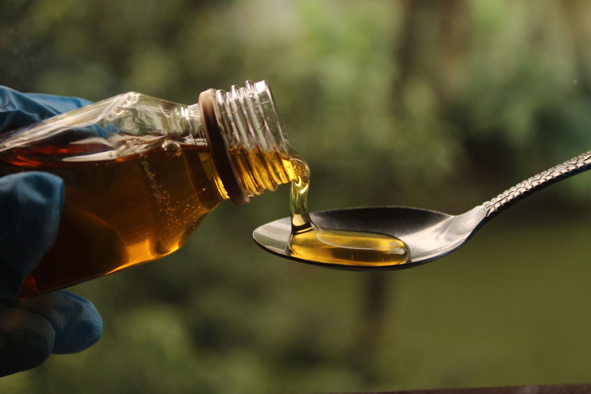 Close-up of golden syrup being poured from a bottle into a spoon.