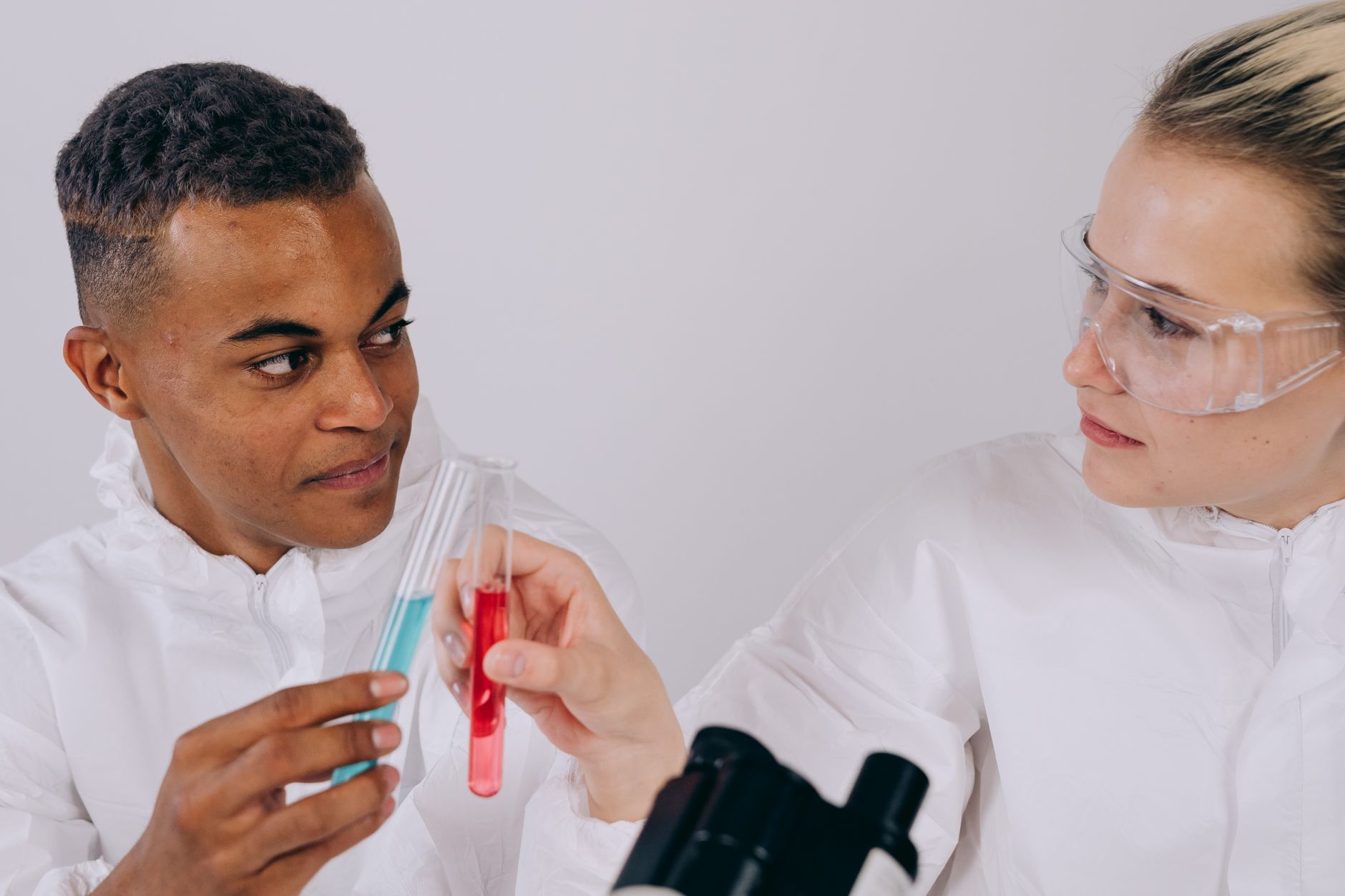 Two scientists in lab coats discussing results with test tubes in a laboratory setting.