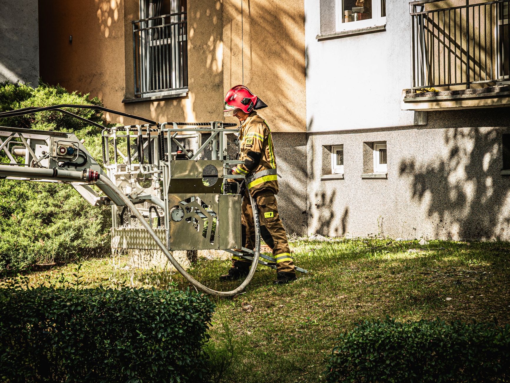 Firefighter operating equipment outside apartment buildings in Wrocław, Poland.