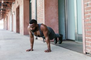A man performs push-ups outside against a brick wall, showcasing strength and fitness.