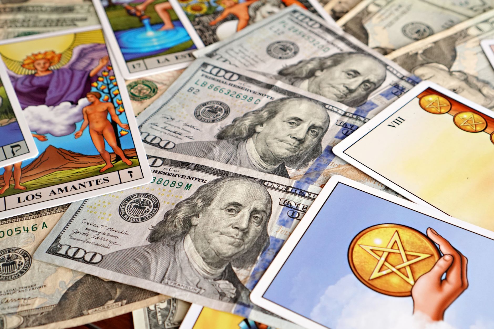 Close-up of tarot cards and US hundred dollar bills symbolizing fate and wealth.