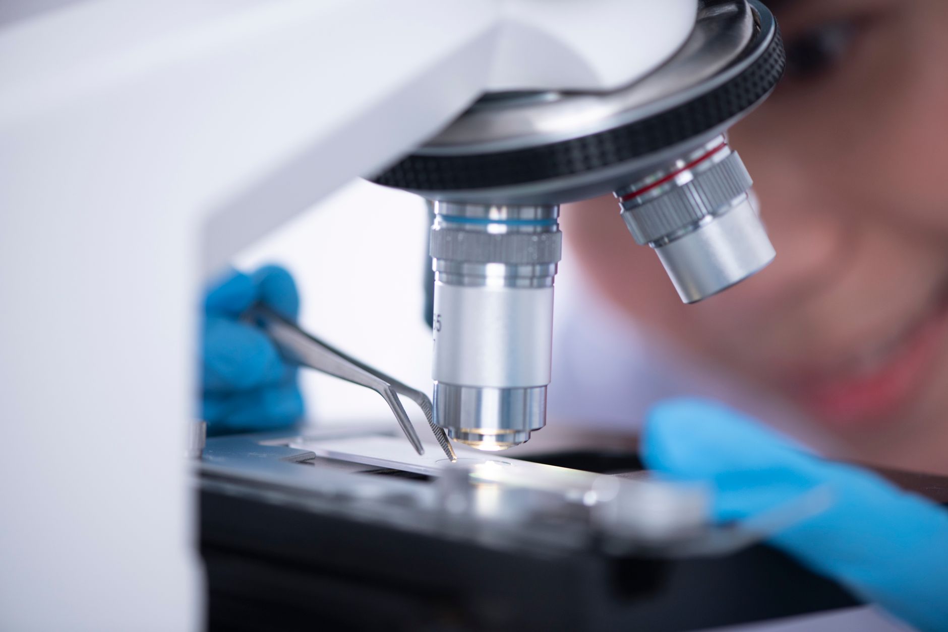 Blurred unrecognizable person placing sample on microscope while making research during work in modern laboratory