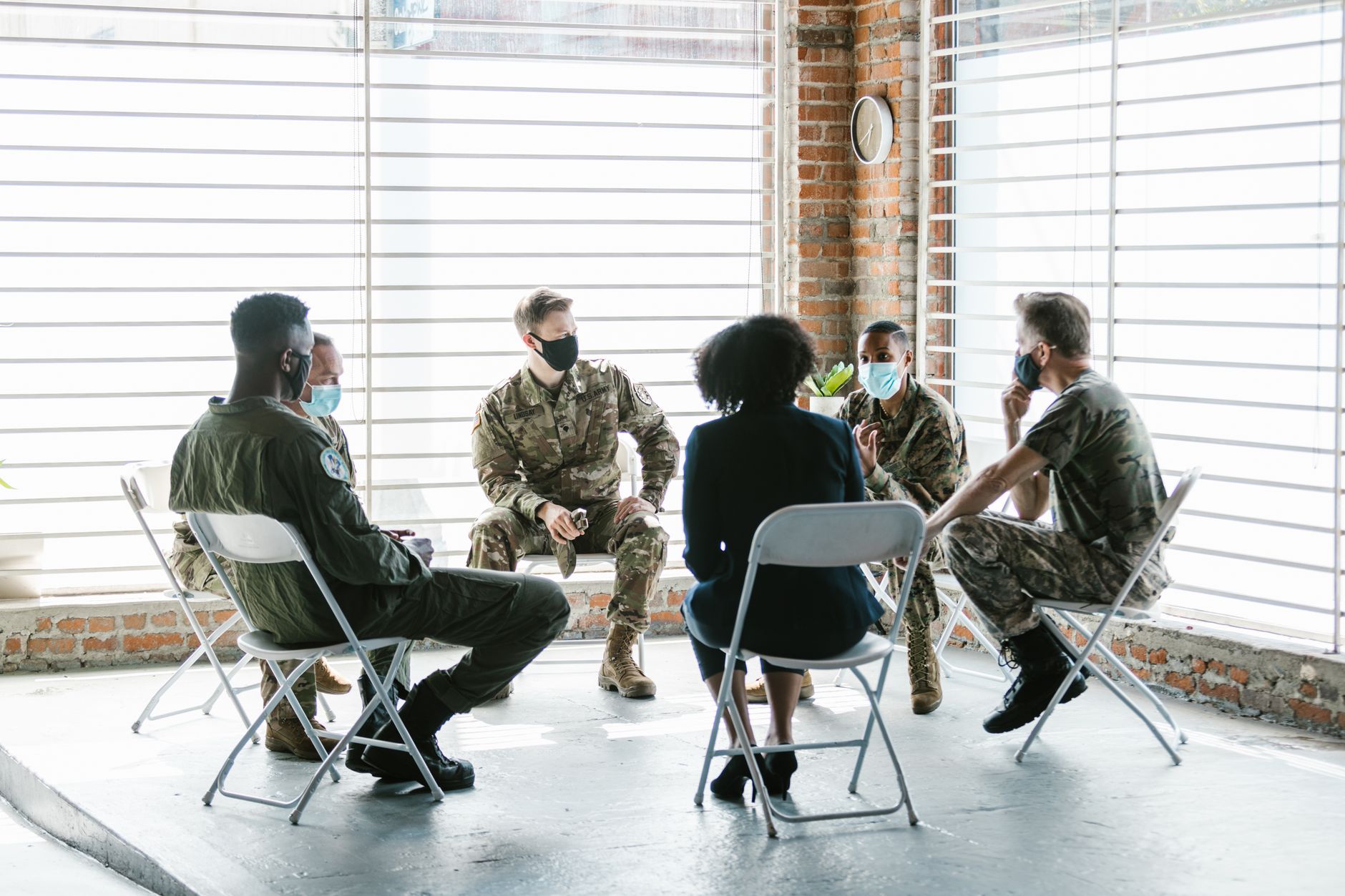 A group therapy session with soldiers in military uniform and face masks indoors.