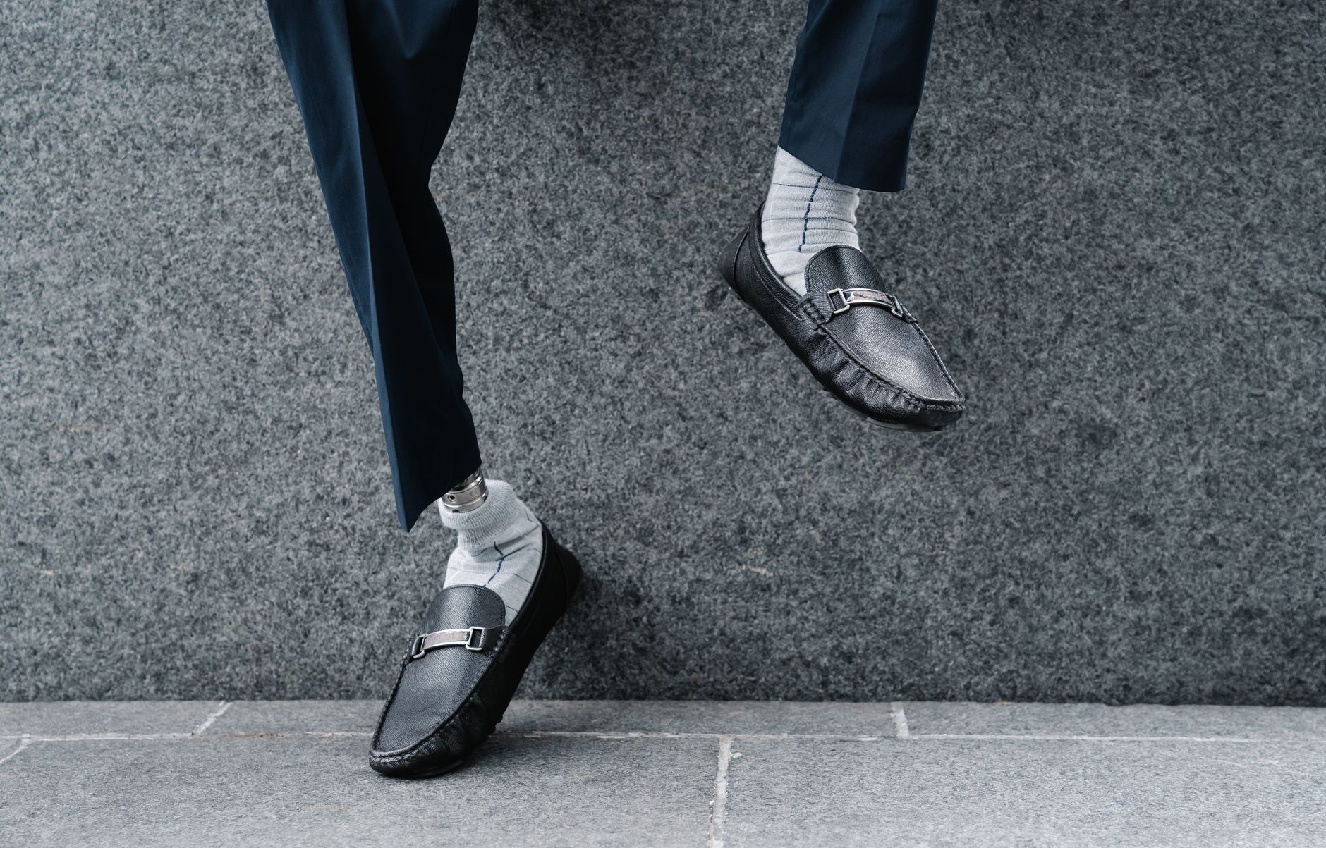 Fashionable shot of a prosthetic leg wearing trendy leather shoes against a stone background.