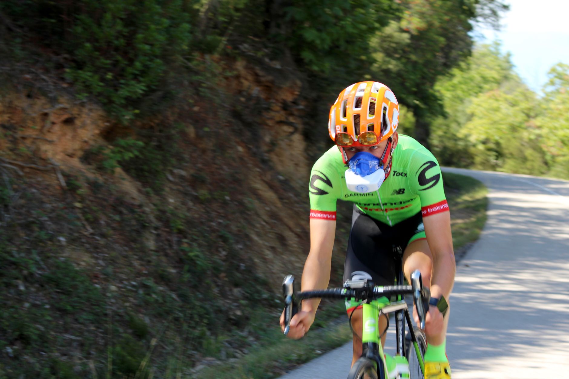 High-performance cyclist using VO2 mask on a winding road, showcasing speed and endurance training.