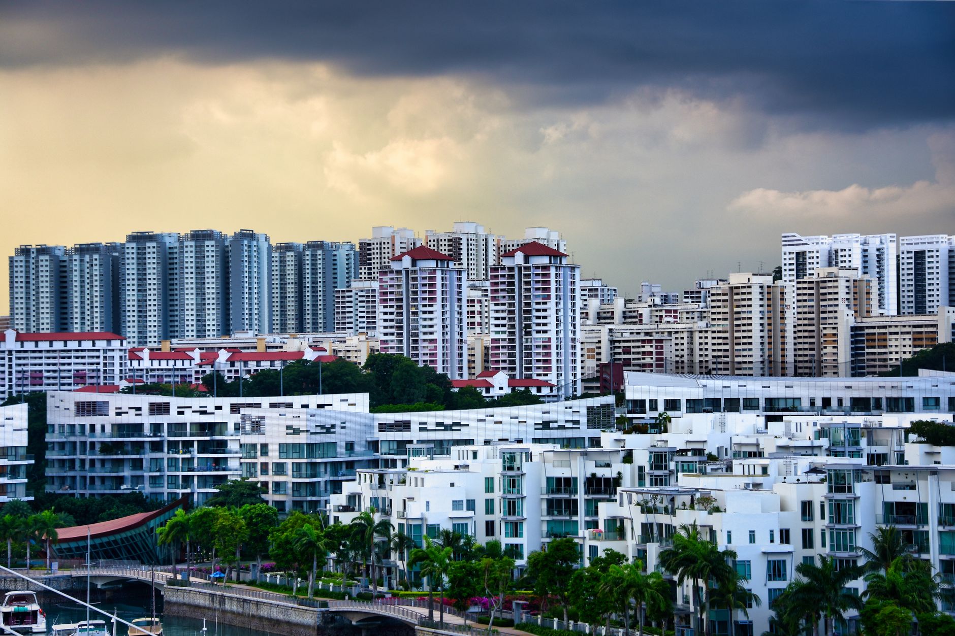 A view of Singapore's modern skyline showcasing high-rise residential buildings against a dramatic sky.