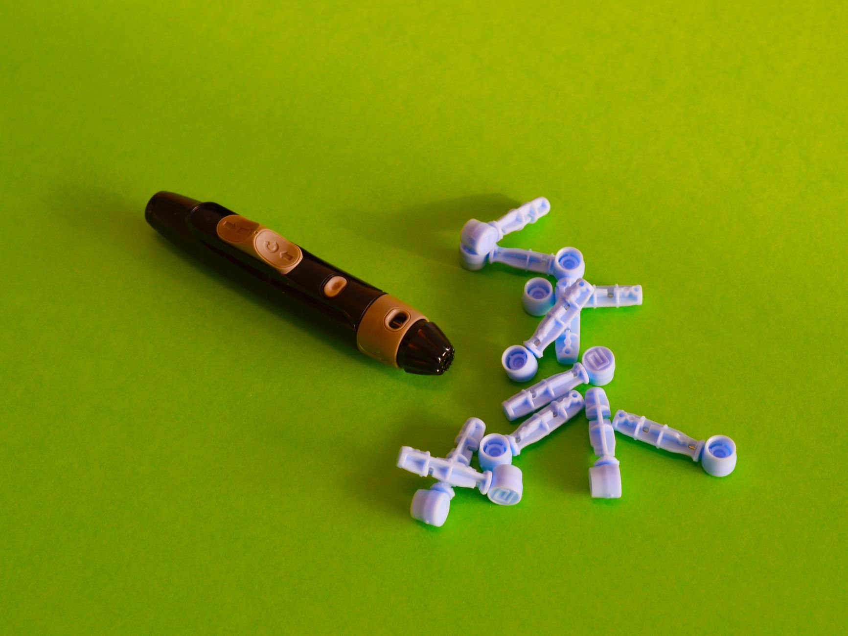 Close-up of a diabetes lancet device with lancets on a vibrant green background.