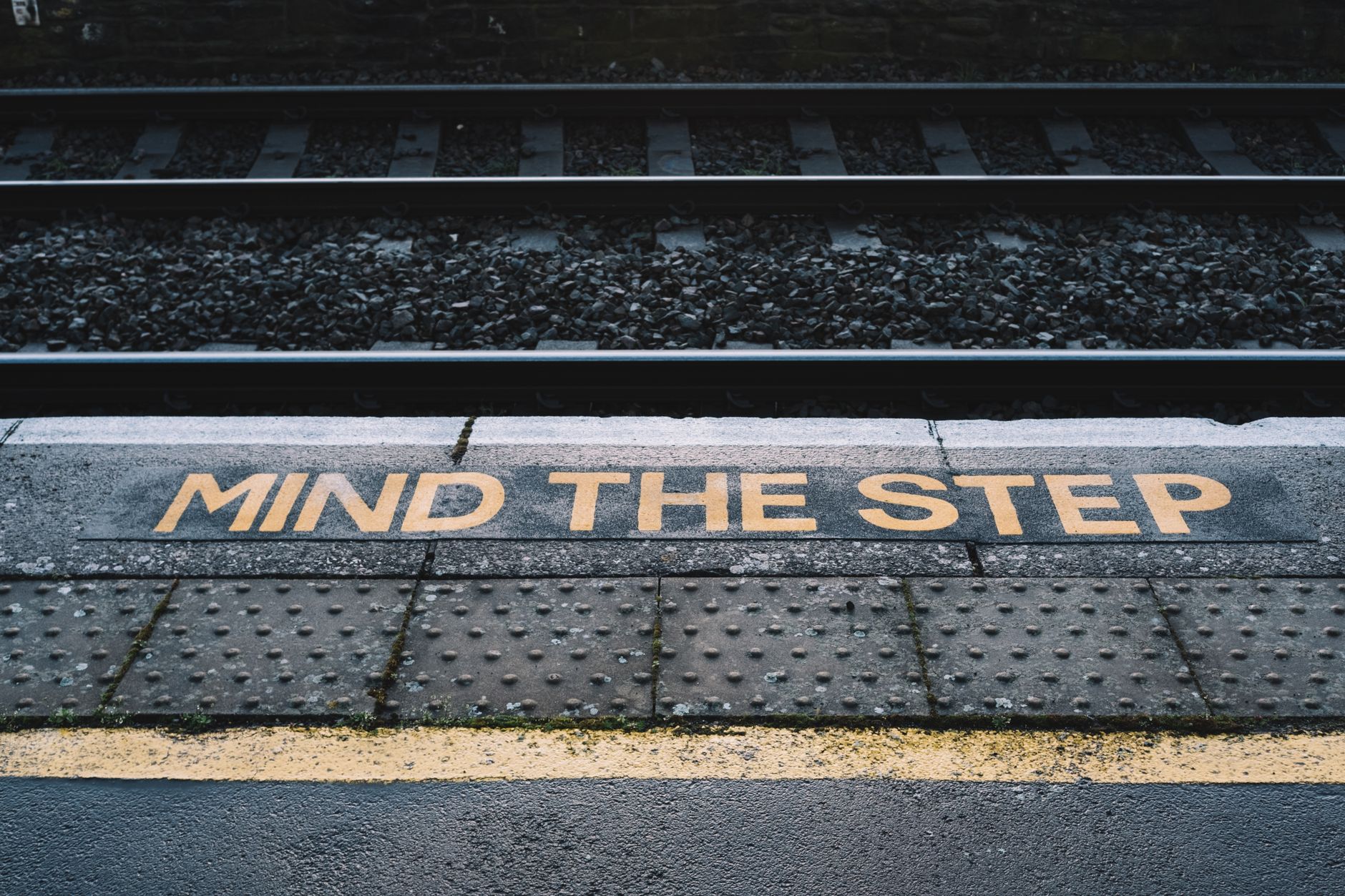 Metal platform with yellow inscription marking near railroad on city street in daytime