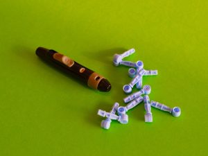 Close-up of a diabetes lancet device with lancets on a vibrant green background.