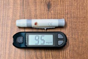 Close-up of a glucometer reading 95 mg/dl with a lancing device, ideal for diabetes and healthcare imagery.