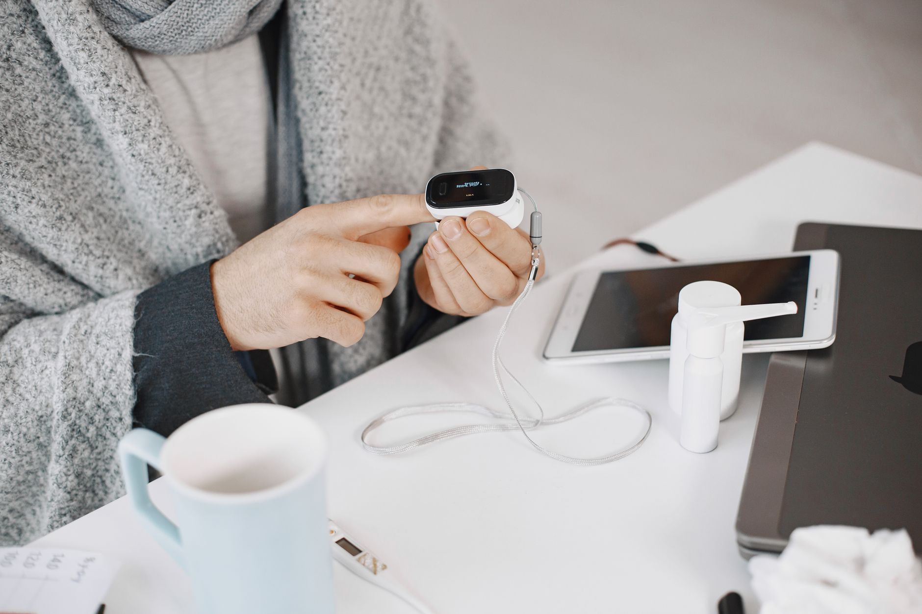 Man in cozy setting reviews a medical device alongside a tablet, focusing on healthcare.