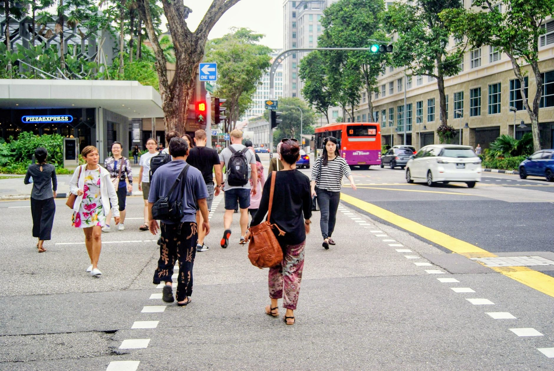 People crossing a busy intersection in Singapore's urban landscape.